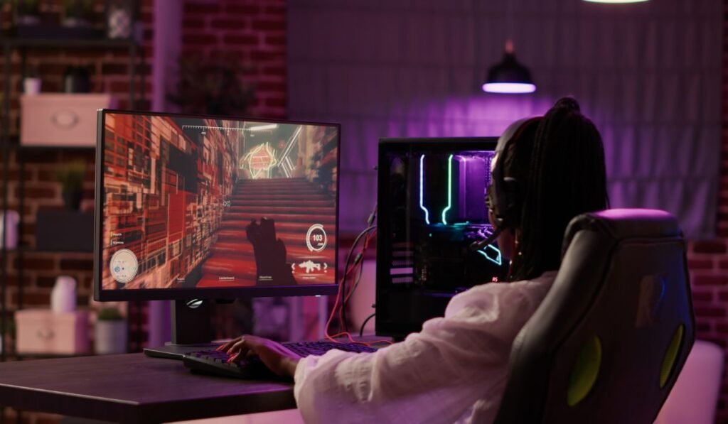 Vue sur l'épaule d'une fille de joueur afro-américaine jouant à des jeux en ligne à l'aide de la configuration d'un ordinateur de jeu