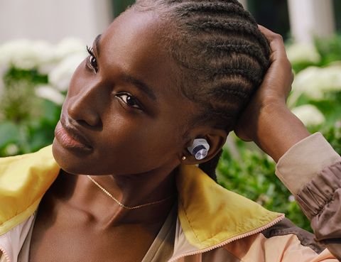 une femme regardant à sa droite avec un écouteur blanc et argenté dans son oreille gauche